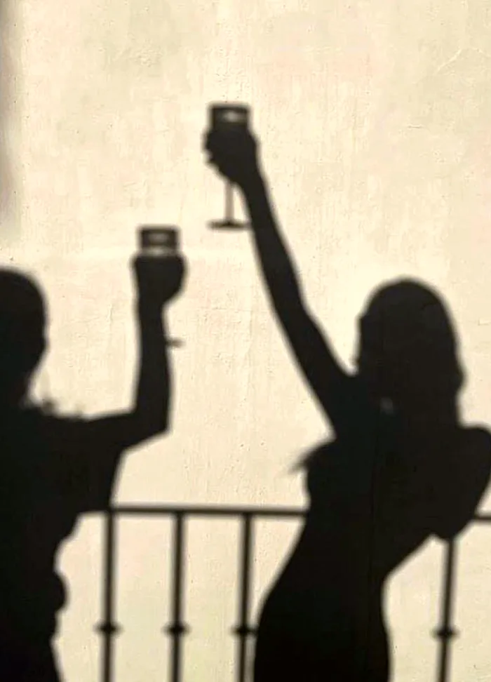 Sombras de dos amigas brindando al sol